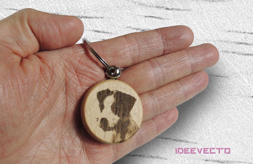 Porte-clés rond dans une main et une photo d'un chiot gravé personnalisé sur du bois