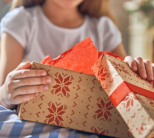 Un enfant ouvrant un cadeau de jeux ou jouets pour Noël ou anniversaire