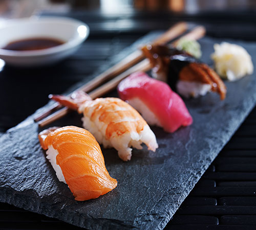 Assiette en ardoise avec des sushis posée sur une table de cuisine