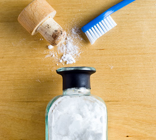 bicarbonate de soude en pot avec une brosse et son bouchon sur une table de cuisine